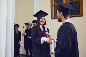 Wall Mural - Graduate students shake hands at university college.