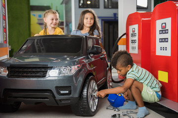 31.07.2017 - Kyiv, Ukraine. Childrens role play center. Two little girls driving car in gas station in game center. Entertainment and educational center for kids.