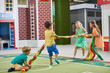 Group of happy children playing tug of war indoor. Gaming room interior with playing kids. Kids amusement park.