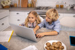 © zinkevych - Two kids sitting at the table and watching a video on internet