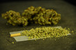 Marijuana Joint being rolled with marijuana buds in background