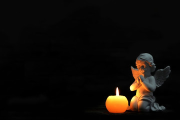 Angel and burning candle on black background