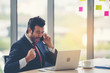 © sunti - Happy businessman celebrate success looking at laptop screen  and listen to the phone in the office.
