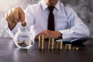 Wall Mural - business man or banker put coin in jar and stacked money to save investment, finance and income concept