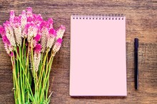 Beautiful Pink Flower ,blank Paper Notepad And Pen On Wooden Table 