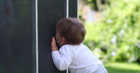 Wall Mural - Baby standing outside leaning on pool fence