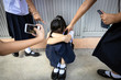 © Satjawat - Problems of bullying at school,sad stressed asian girl student crying sitting on the floor,group of hands pointing finger to scared schoolgirl, bullying victim being video recorded on a mobile phone