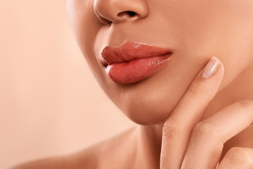 Wall Mural - Young woman with beautiful full lips on peach background, closeup