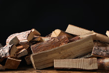 Cut Firewood On Table Against Black Background
