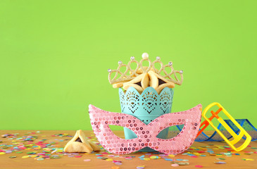 purim celebration concept (jewish carnival holiday) over green wooden background