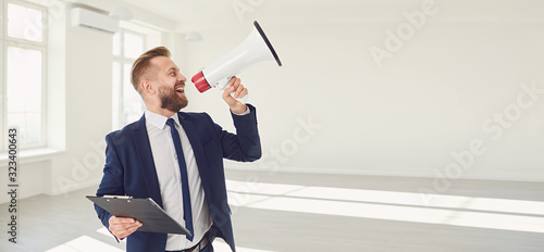 Fotografía Male real estate agent shioting in megaphone smiling in white real estate room a