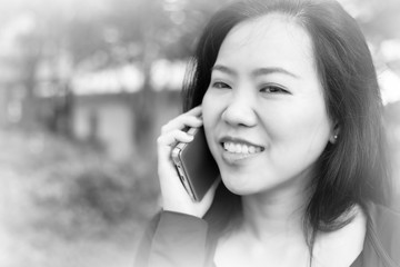 Asian woman talking on smart phone at park. Communication concept. Extrovert characteristic. chit chat with friend. black and white tone