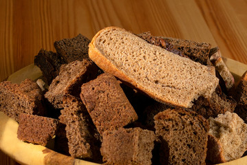 wooden plate with dried pieces of black and white bread close-up