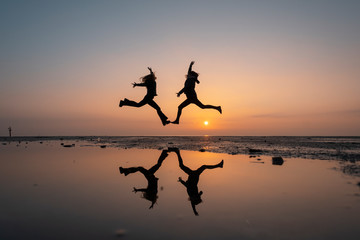 silhouette of two girls jumping cheerful and happiness during sunrise