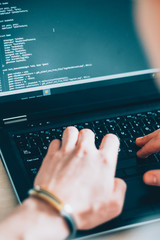 Software development. Information technology. Male programmer writing code on laptop.