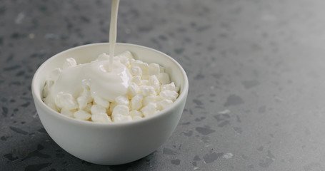 Wall Mural - yogurt pour into cottage cheese in white bowl on concrete surface