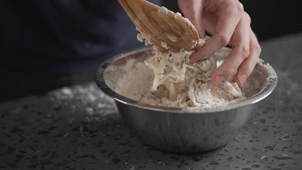 Wall Mural - man mixing wet ingredients into flour in steel bowl on concrete countertop