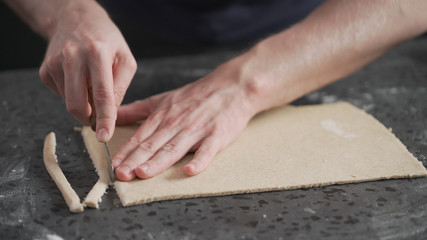 man cutting flat dough with knife