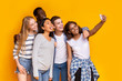© Prostock-studio - Cheerful group of multiethnic friends taking selfie over yellow background
