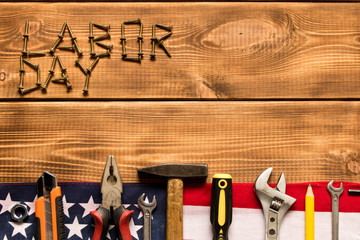 Wall Mural - Labor day. American flag and various tools on a wooden background. The concept of labor day. Empty space for text.