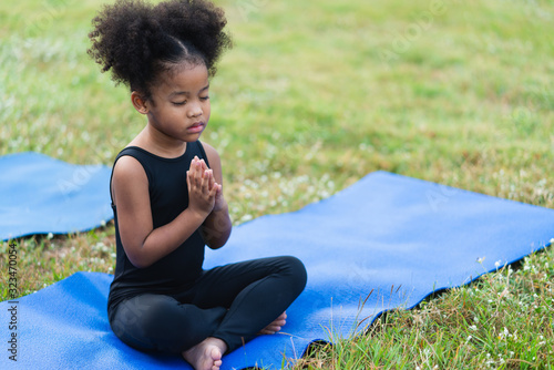 Cuadros en Lienzo African american little girl sitting on the roll mat practicing meditate yoga in
