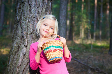 Wall Mural - Cute little girl with wicker basket posing and walking through the woods. Summer holiday.