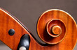 Nahaufnahme einer Celloschnecke mit eleganter Holztextur und Stimmwirbel vor braunem Hintergrund