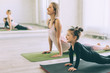 Sporty woman and child girl doing stretching exercise on yoga mat in front of mirror in fitness class