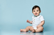 © FAB.1 - Little child in white bodysuit as vest with bow-tie, barefoot. He smiling, sitting on the floor against blue background. Close up