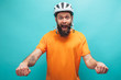 © San4ezz007 - Portrait of handsome hipster guy with beard wearing blank orange t-shirt and white bike helmet pretending to ride a bicycle, isolated on blue studio wall.