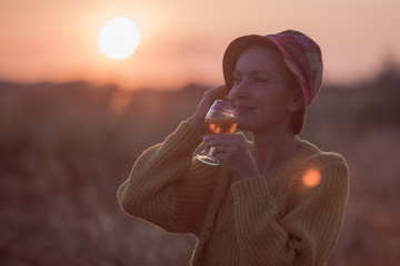 Woman with a cocktail over suset sky in orange colors