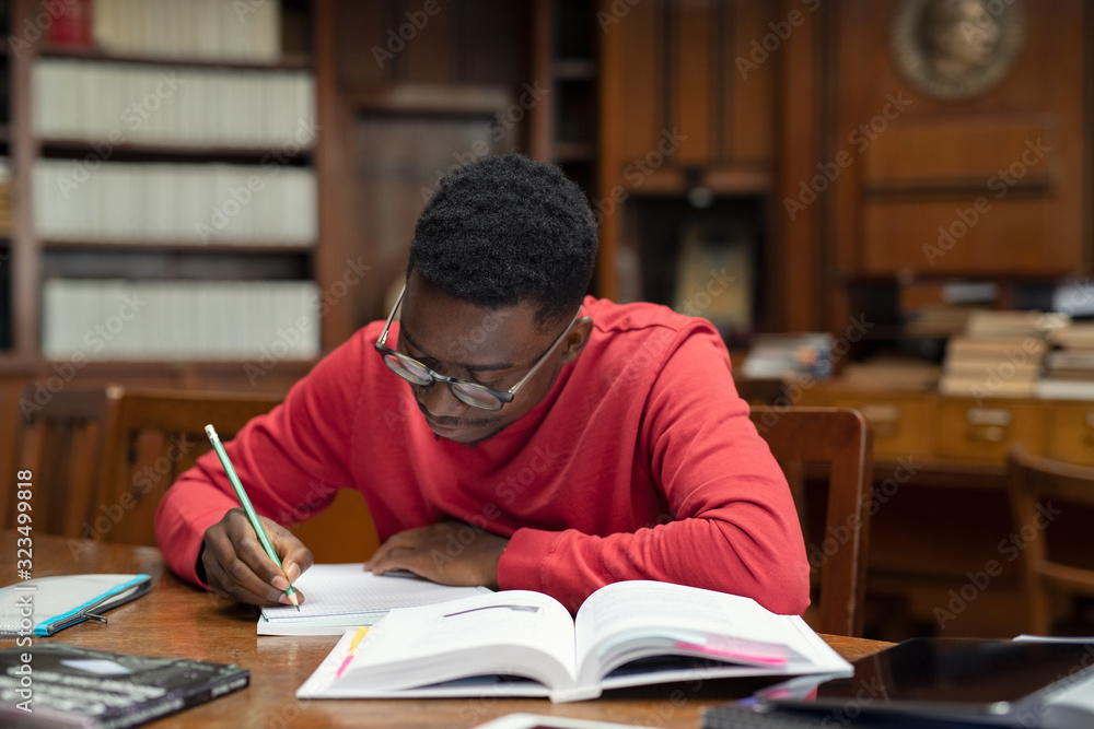 Student in library studying for exam - obrazy, fototapety, plakaty 