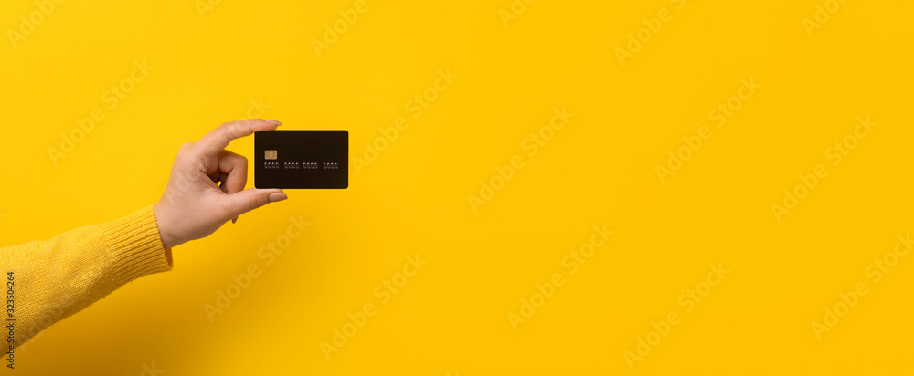 bank card in hand over yellow background, panoramic mock-up - obrazy, fototapety, plakaty 