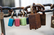 pastel colored and rusty love padlocks on metal chain, close up