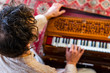 © Valmedia - High angle view of young male shamanic playing kirtan music using musical instrument harmonium for meditation and positive vibrations