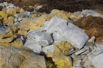 Wall Mural - garbage from white bags and pieces of yellow glass wool in a heap in nature on a sunny day