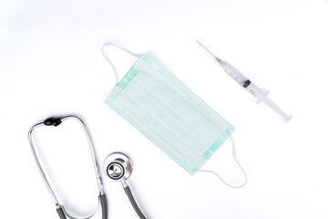 Stethoscope and syringe around face mask in white