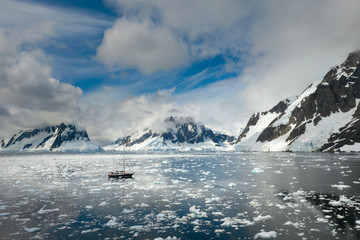 Wall Mural - floating yacht in calm water of strait with icebergs