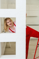 Wall Mural - Beautiful girl makes repairs in a bright white room