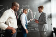 © Svitlana - A great place for a great education. Diverse employees, traders standing near blackboard full of charts, while discussing the strategy of work. Horizontal shot