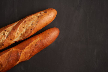 Two crispy french baguettes lie on an old wooden table with free space for text