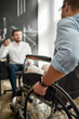 © Svitlana - Cropped photo of office worker in a wheelchair discussing something with his male colleague while working together in the modern office. Disability concept