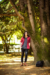 Wall Mural - a young man with long hair,rock style, stands near a tree