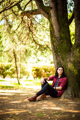 Wall Mural - young man with long hair,rock style, summer,sitting near a tree