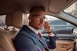 © Svitlana - Working from everywhere. Handsome mature man in full suit adjusting headphones while driving a car
