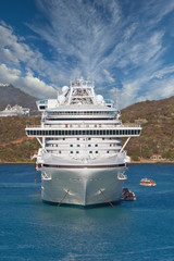 Wall Mural - A white cruise ship anchored in a bay with people loading into lifeboats