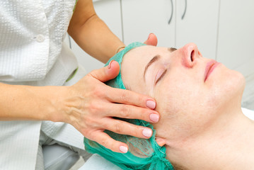 Beautician applies a natural moisturizing mask to the face of a young beautiful woman. Anti-aging mask and wrinkles for problem skin. Cosmetology concept. The cosmetologist performs the procedure to