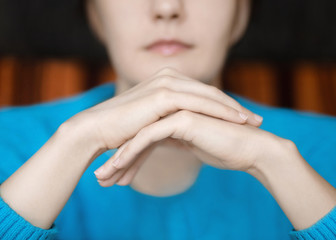 Woman's hands Close-up photo Young woman is sitting clasped hands in front of face