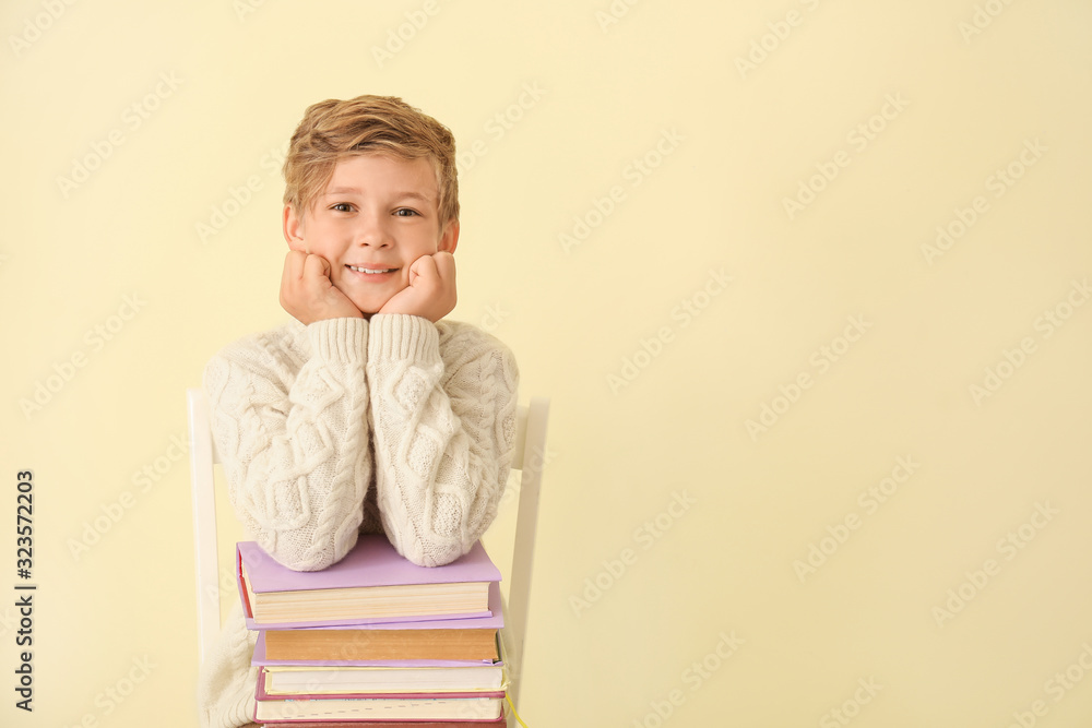 Little boy with books on color background