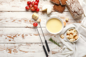 cheese fondue with snacks on white wooden background